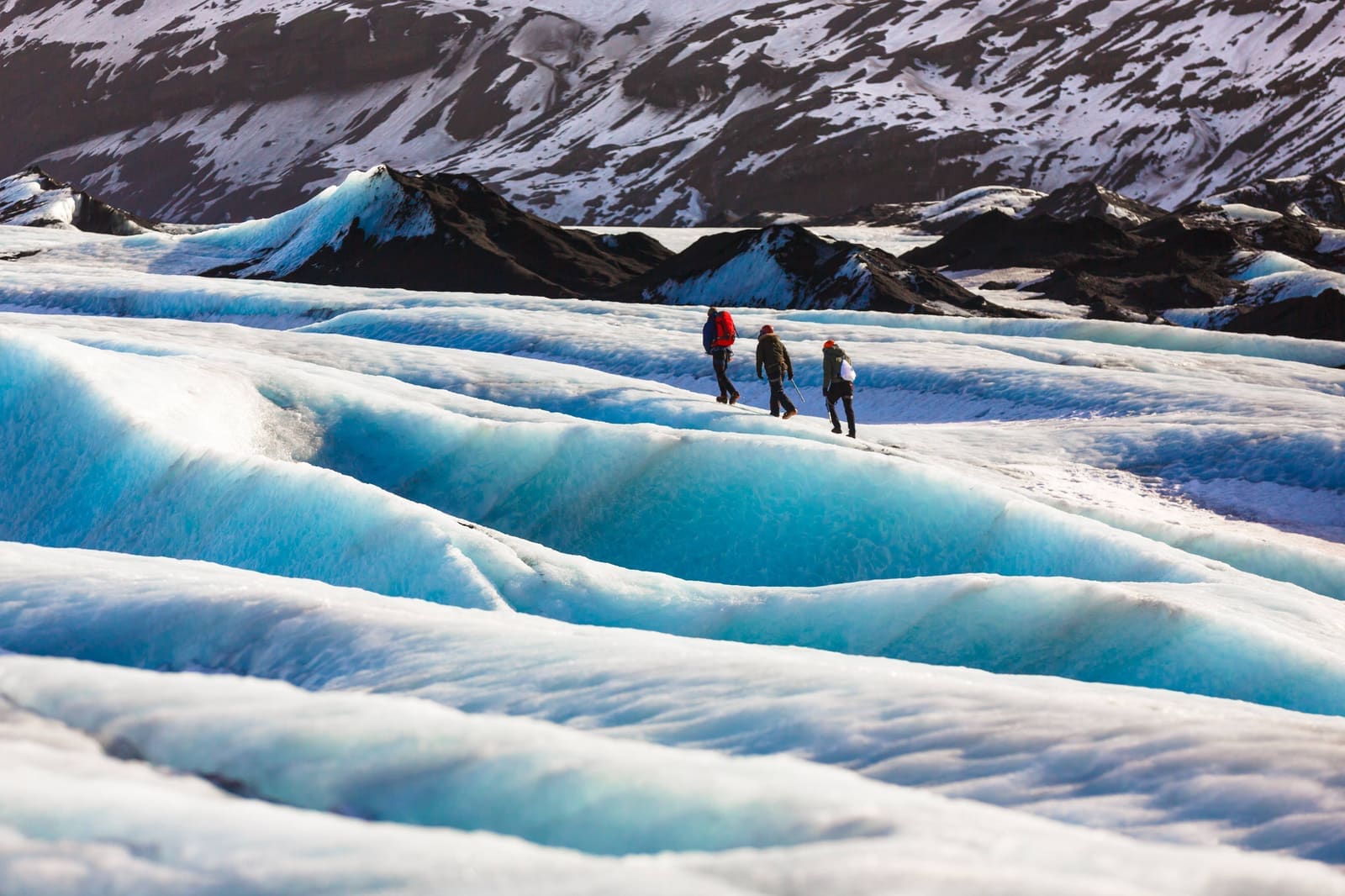 Guided hikers crossing blue ice on Sólheimajökull Glacier in South Iceland.