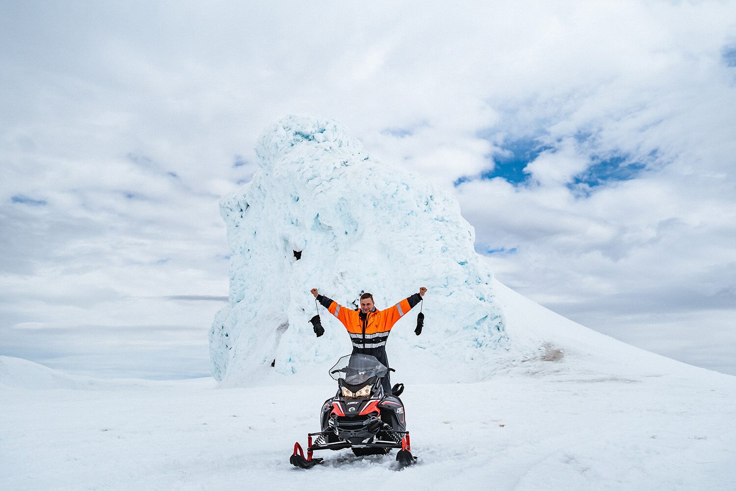 Snowmobilers riding across an Icelandic glacier under open winter skies.