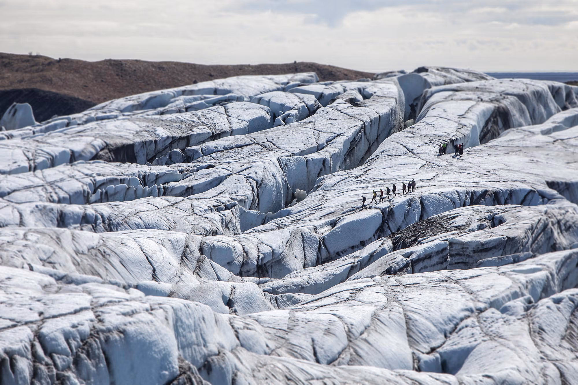 A guide checking glacier gear before hikers walk onto the ice.