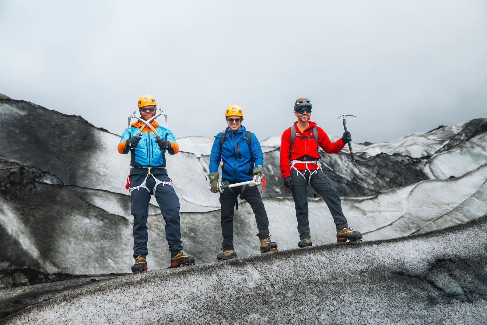 Guided hikers moving across the blue ice of Sólheimajökull with glacier ridges behind them.