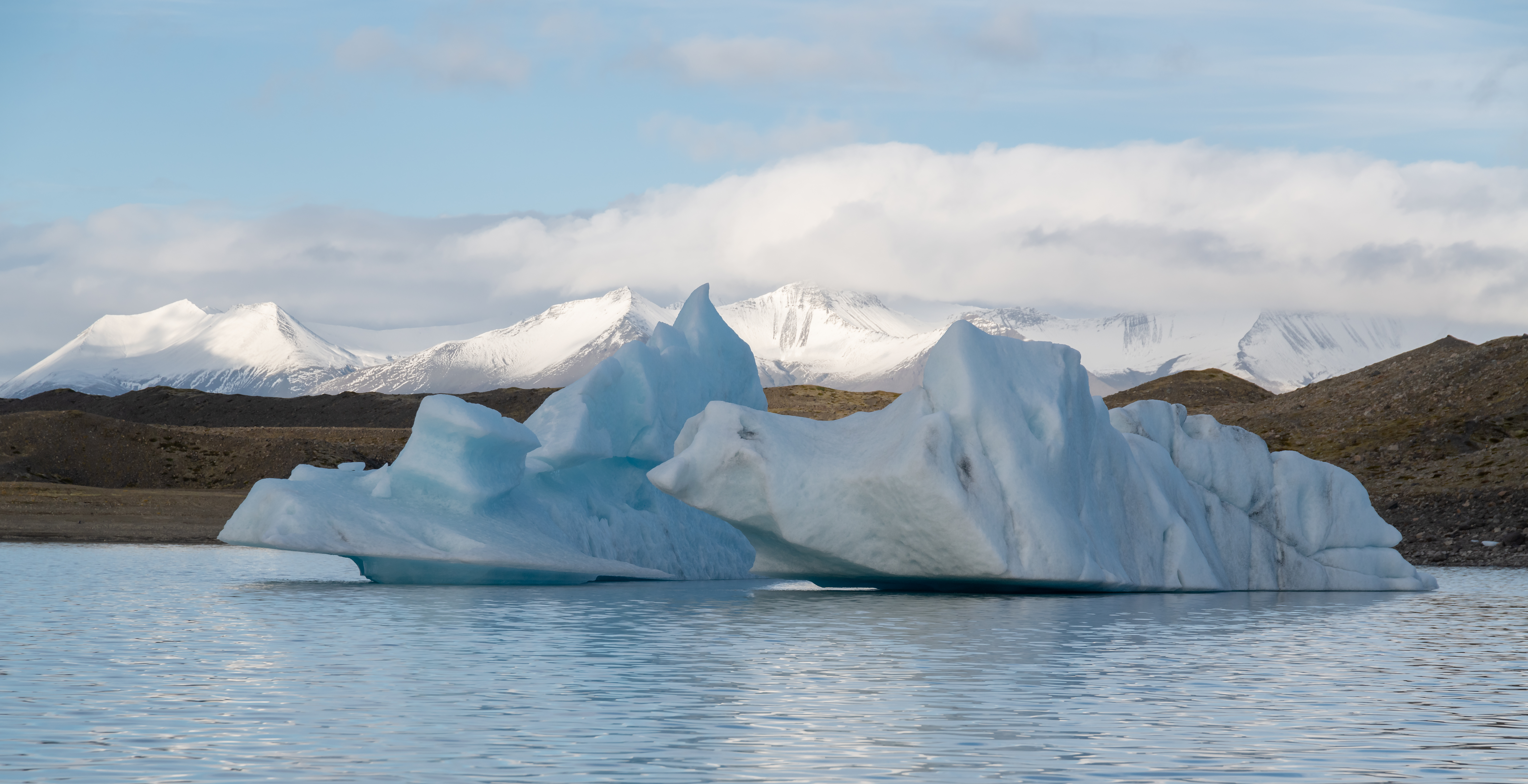 Blue icebergs floating below snowy mountains in South-East Iceland