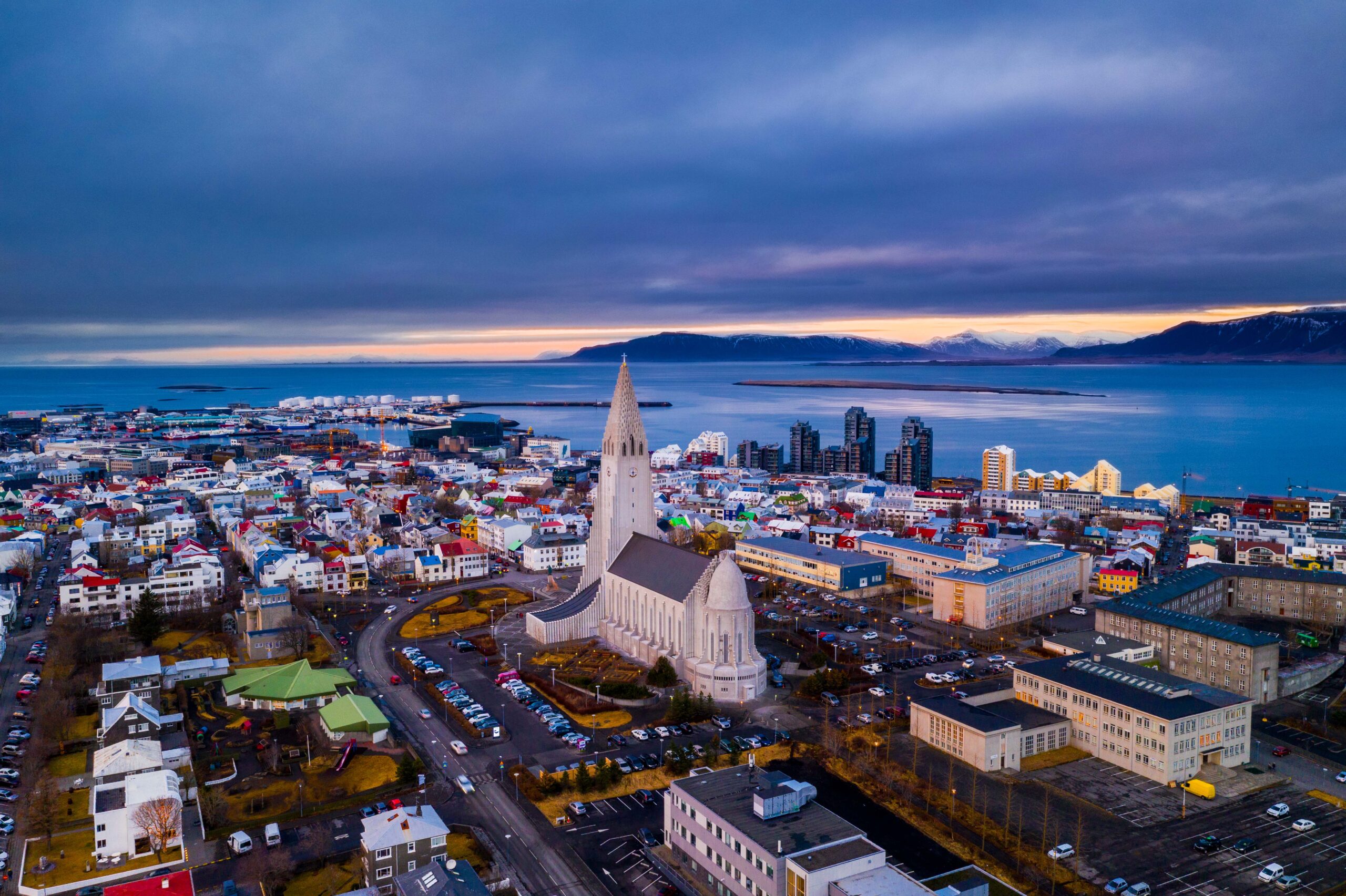 Aerial view over Hallgrímskirkja, central Reykjavík, the harbor, and mountains across the bay.