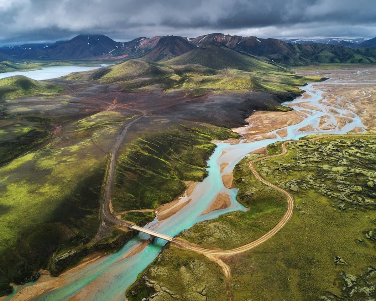 Aerial view of Landmannalaugar with braided water, dark lava, and colorful Highland slopes.