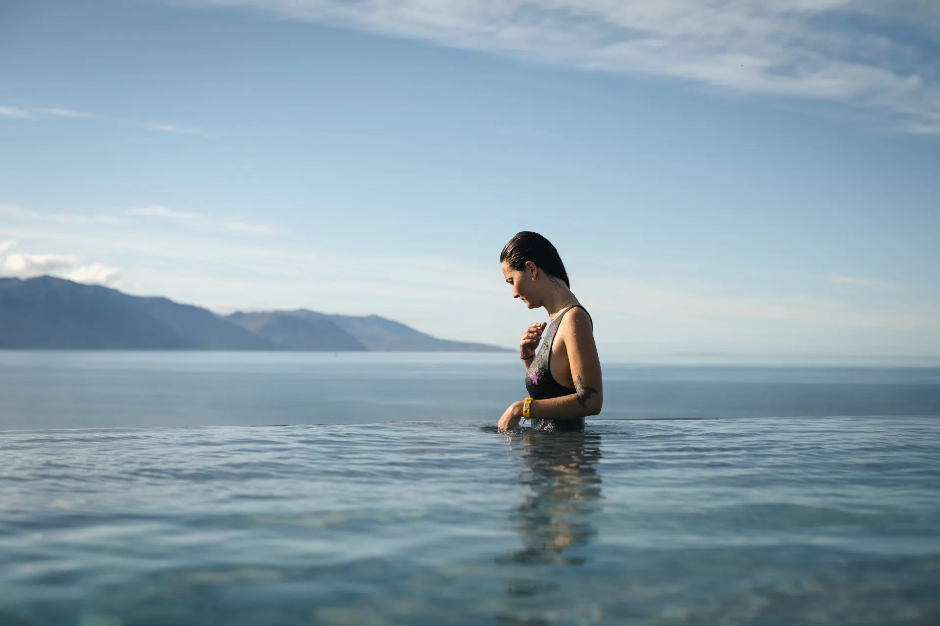 A bather in a geothermal sea bath with North Iceland mountains beyond