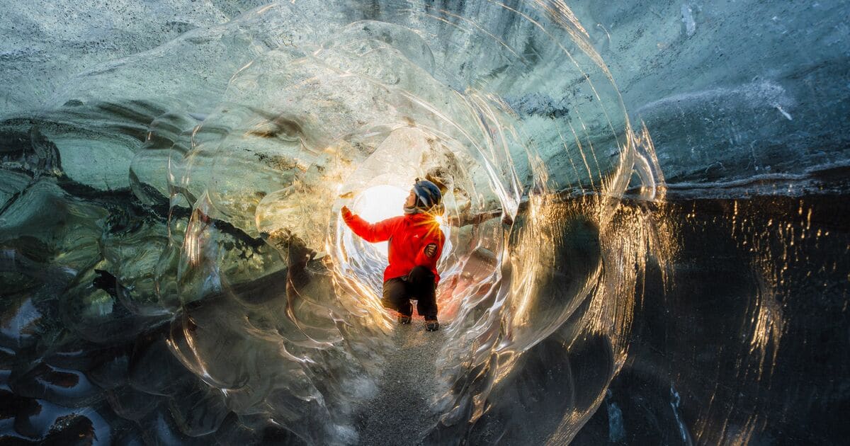 Visitor inside a winter blue glacier ice cave in Iceland.