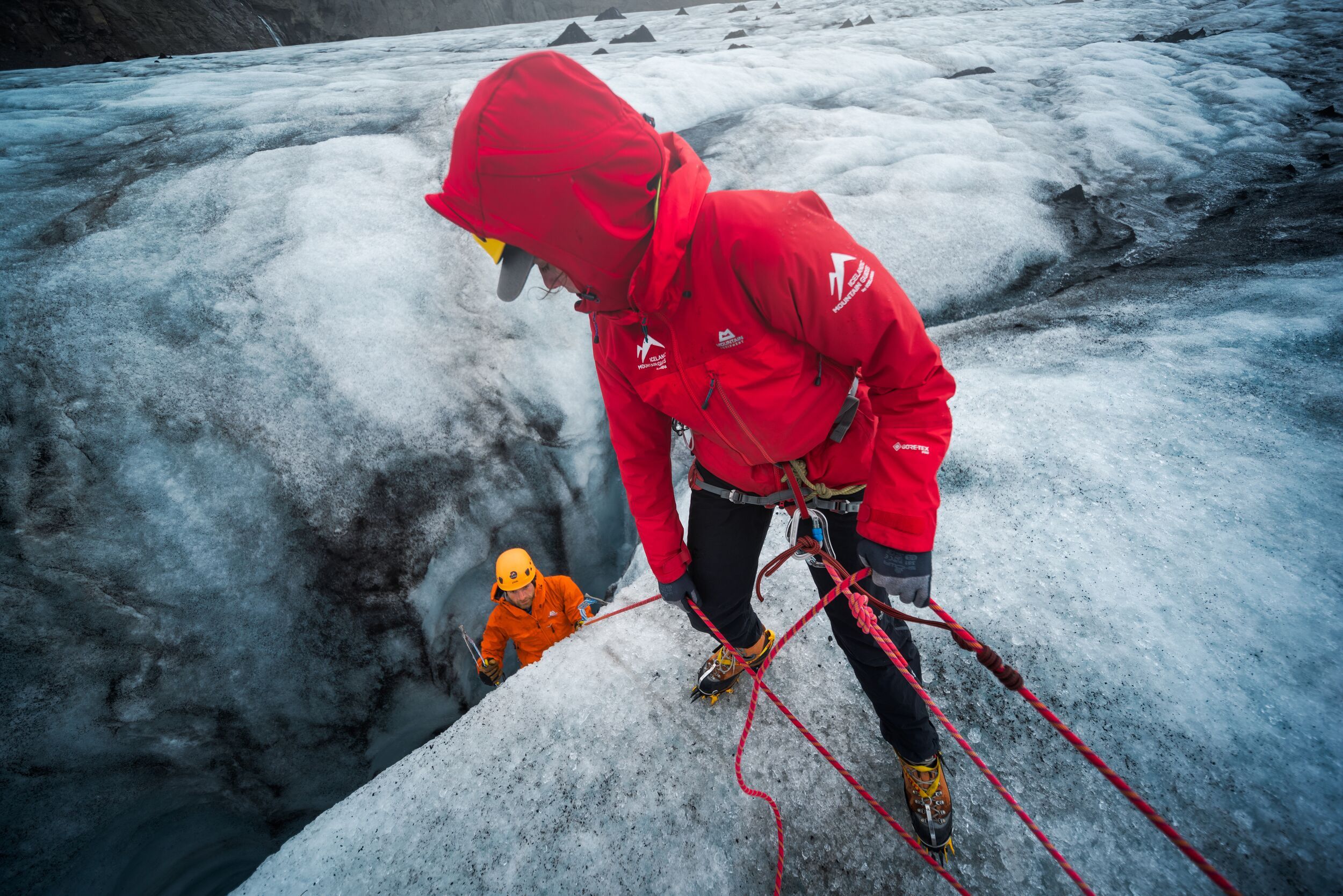 Two roped climbers working at the edge of a glacier crevasse