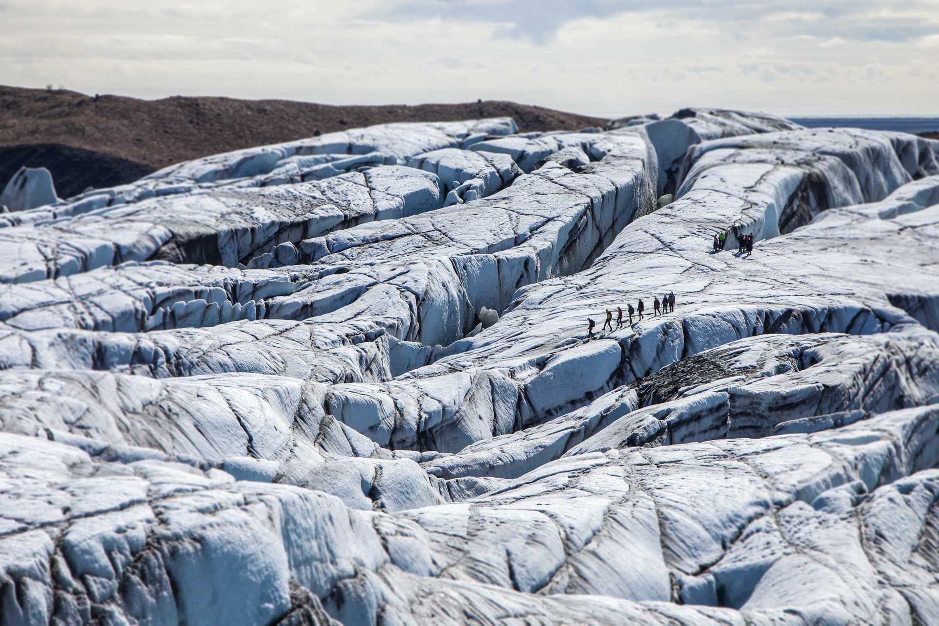 Broad view of crevassed glacier ice crossed by a small guided group