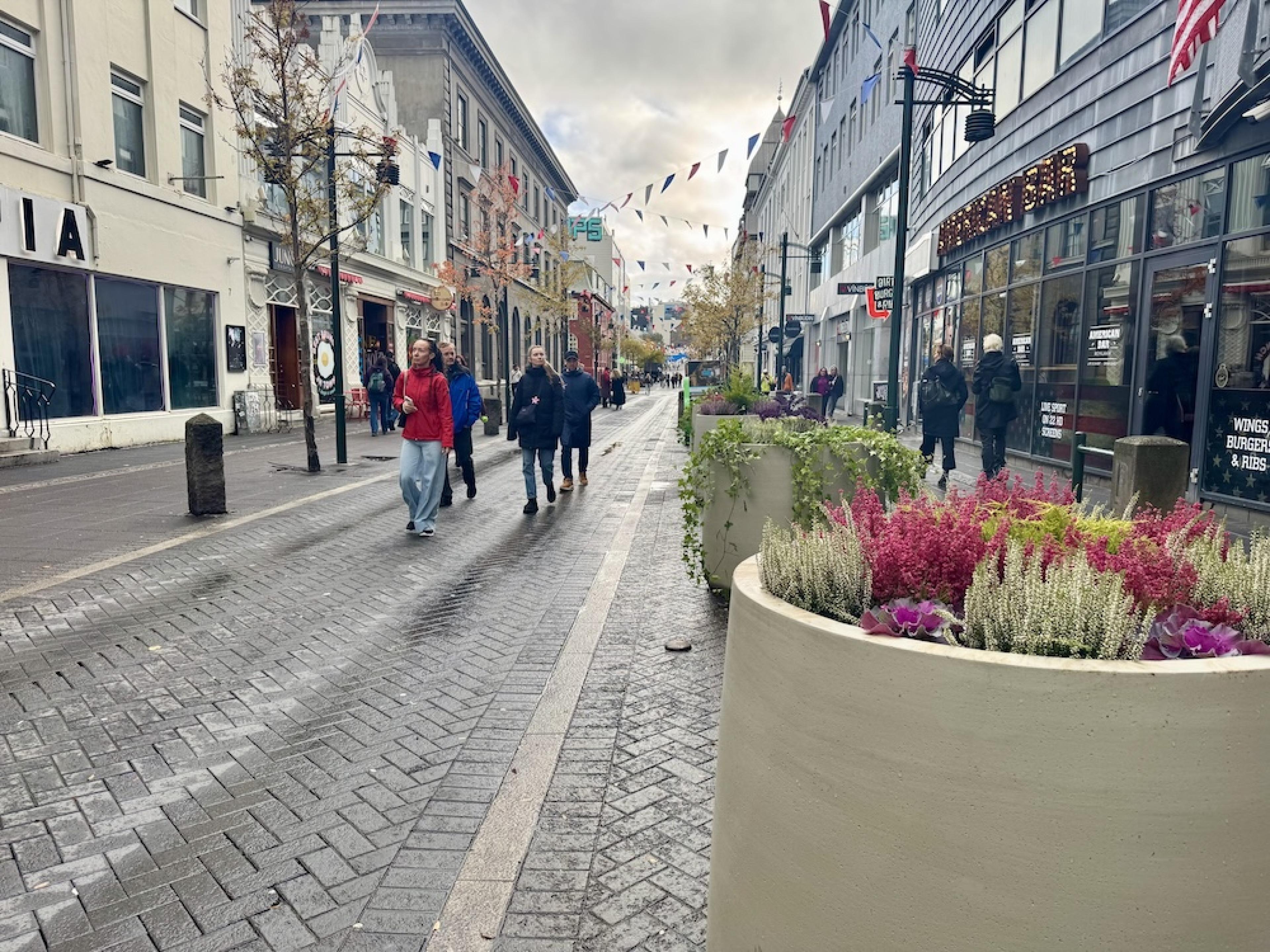 People walking along wet Austurstræti in central Reykjavík