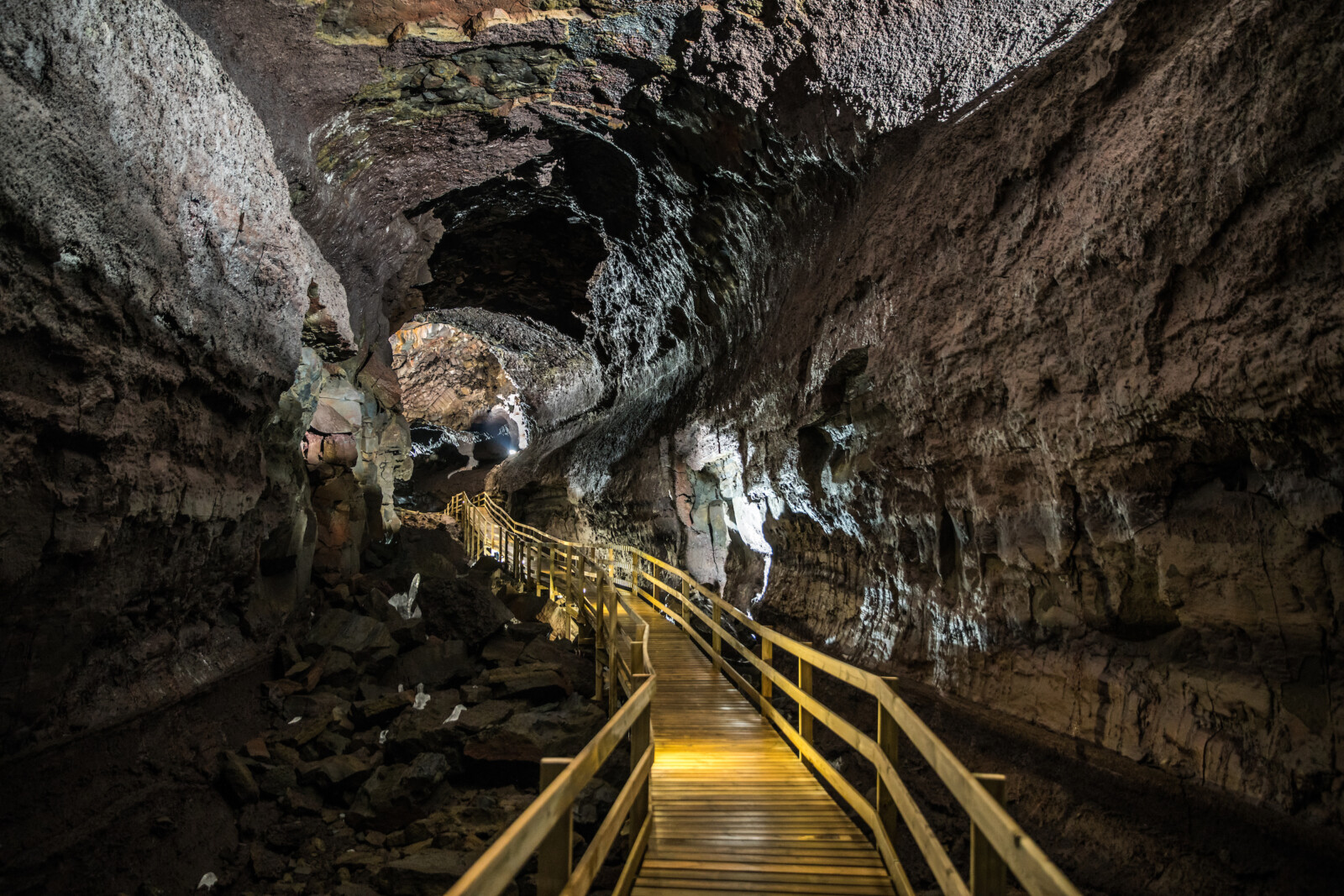 Wooden walkway curving through the broad interior of Víðgelmir lava cave in West Iceland