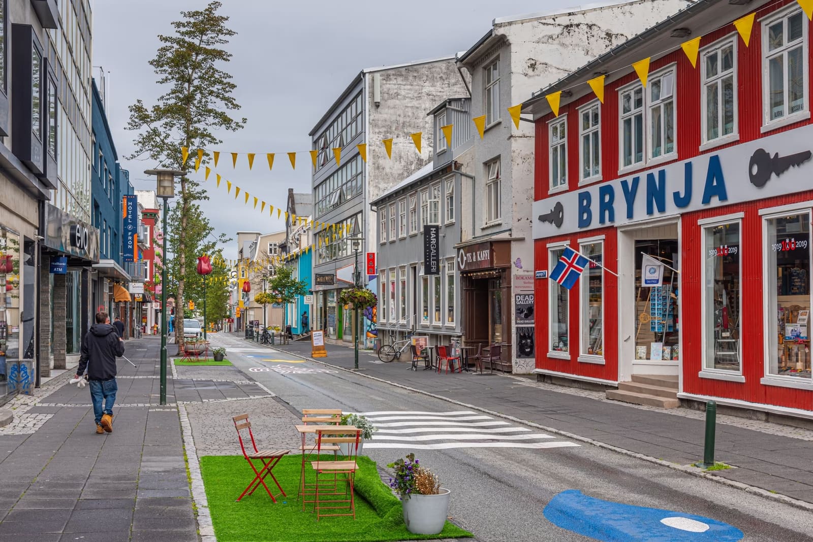 Colorful storefronts, flags, and pedestrians along Laugavegur in Reykjavík