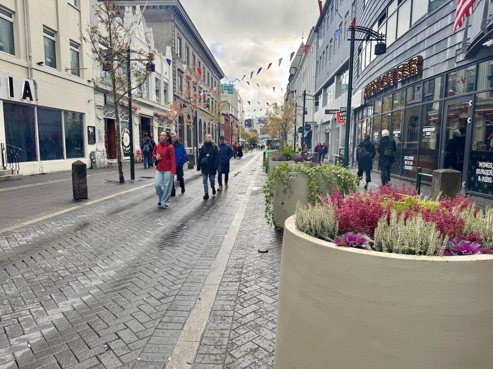 People walking along wet Austurstræti in central Reykjavík