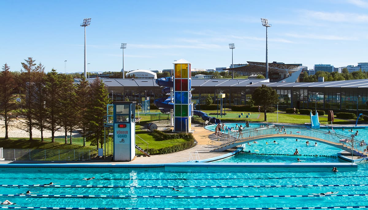 Swimmers using the outdoor pools, lanes, and slides at Laugardalslaug in Reykjavík