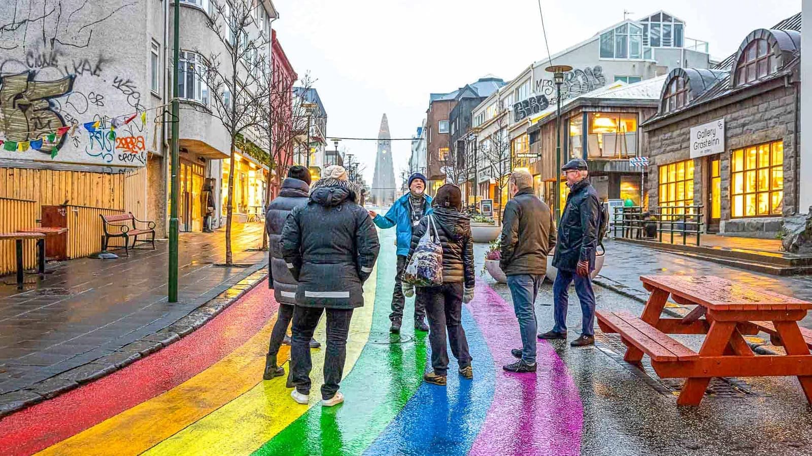 A small walking group on wet Rainbow Street in Reykjavík with Hallgrímskirkja ahead