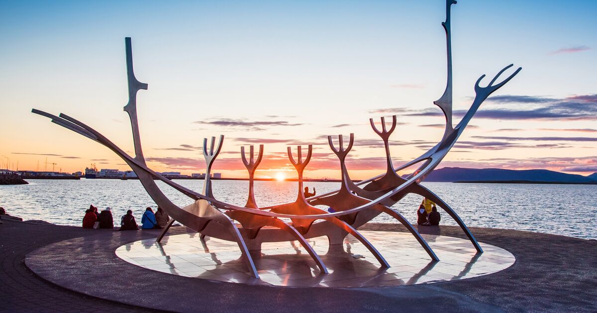 Visitors sitting beside the Sun Voyager sculpture at sunset on Reykjavík's waterfront