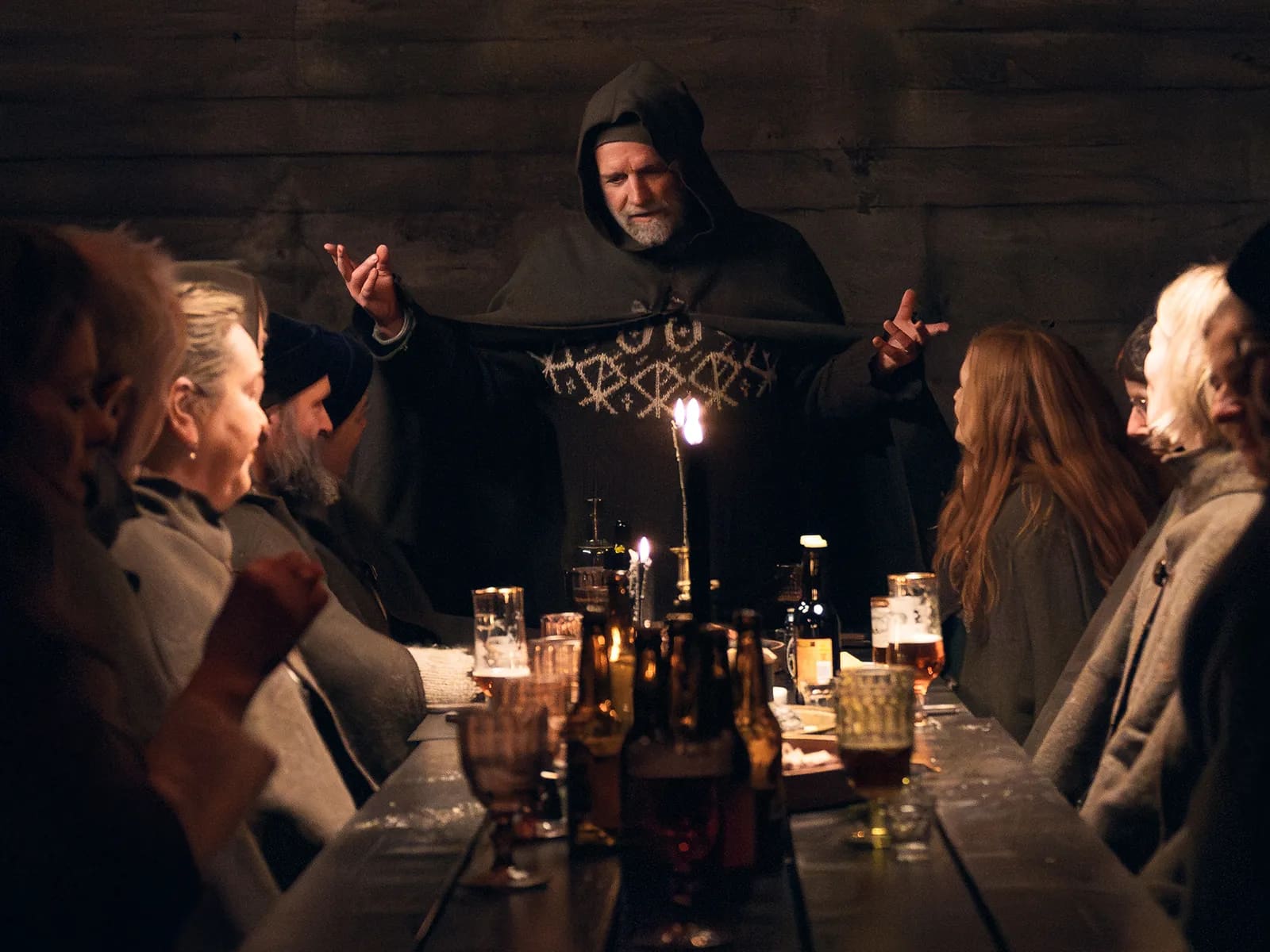 Storyteller addressing guests around a candlelit table at a South Iceland farm