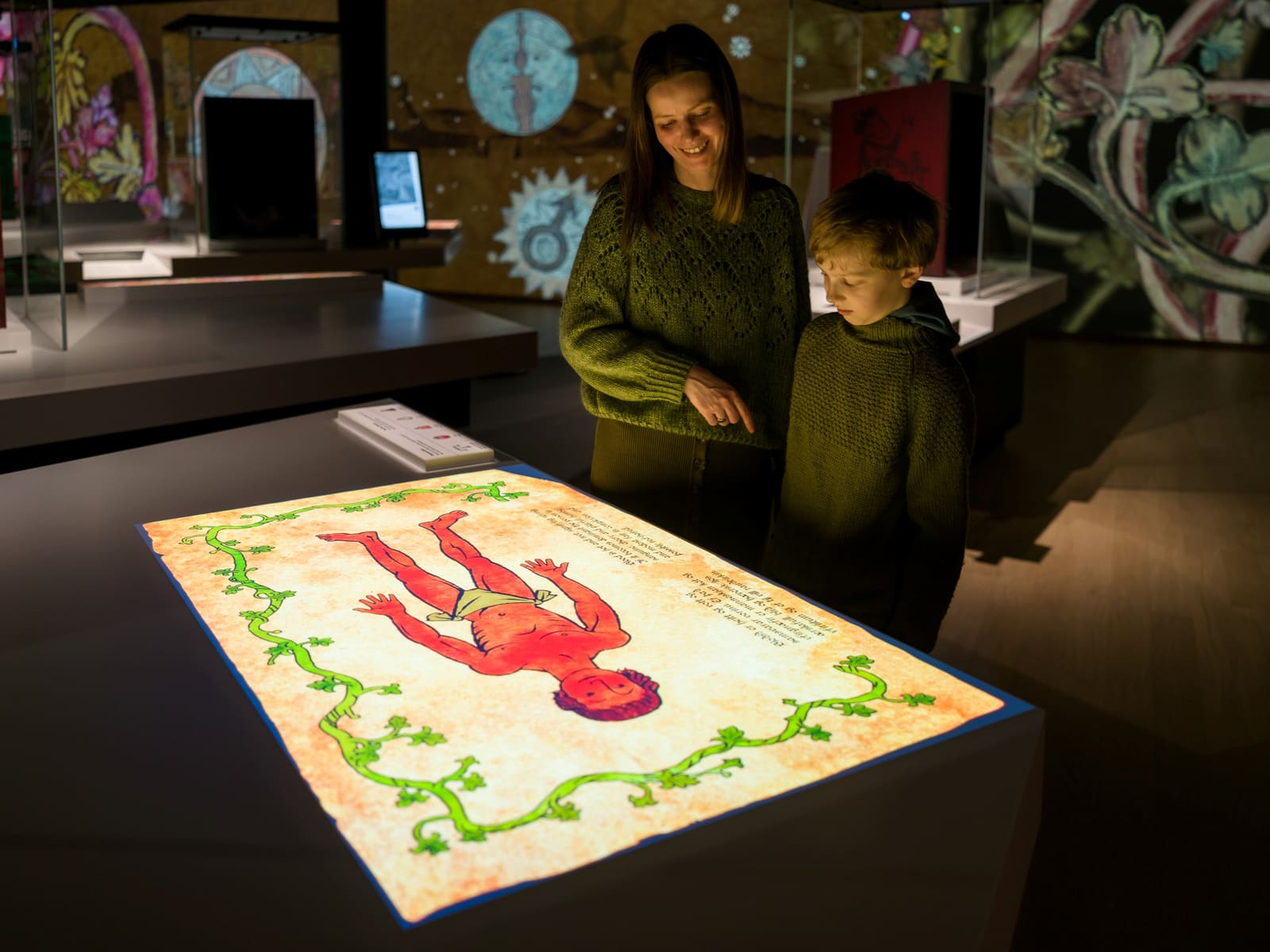 Adult and child using an illuminated manuscript display inside World in Words