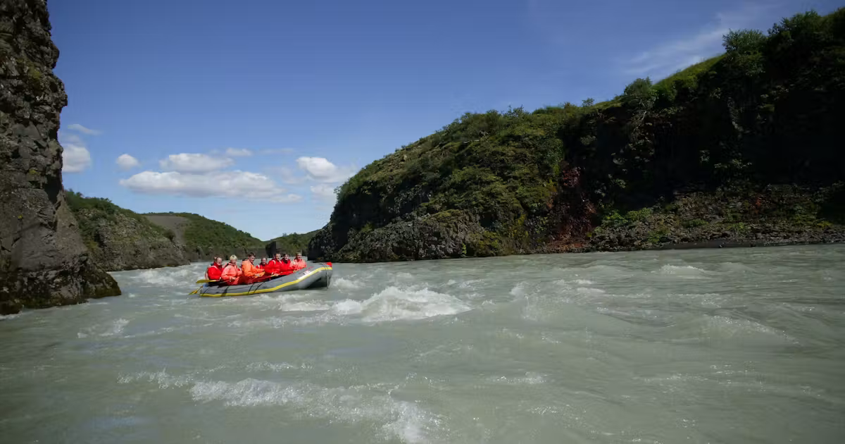 A guided rafting group paddling through a glacial river canyon in Iceland