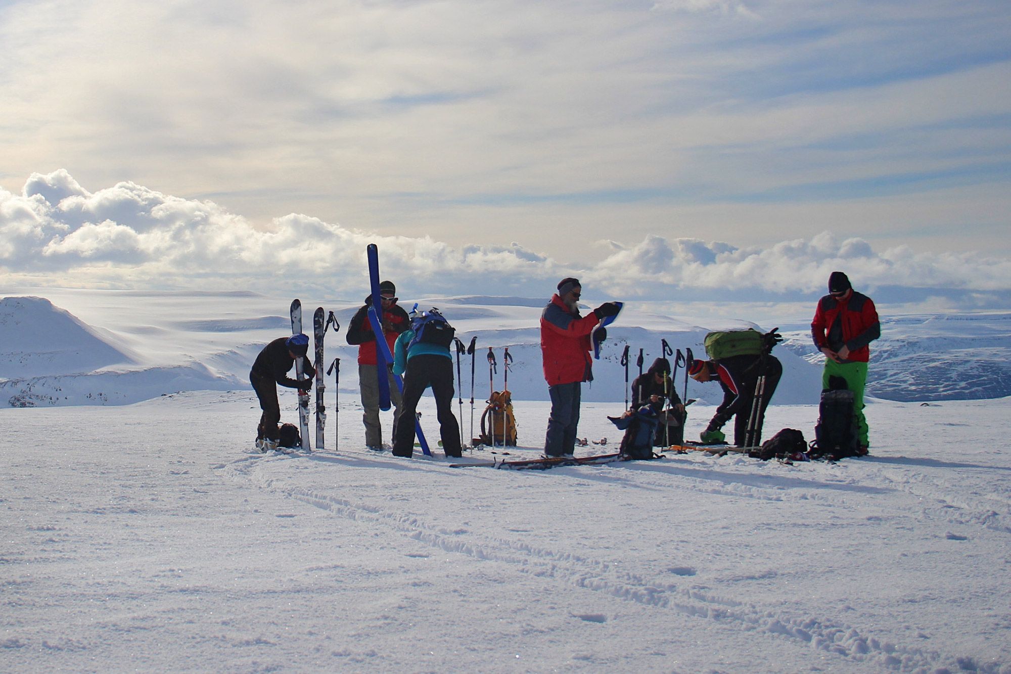 Ski touring group handling skis, poles and backpacks on a snowy North Iceland mountain