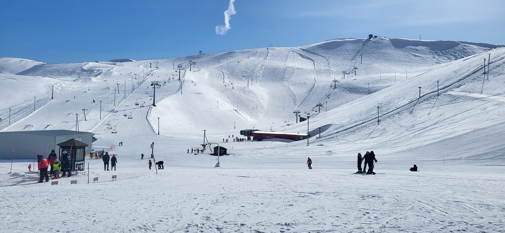 Skiers at the Bláfjöll base below lift-served snowy slopes near Reykjavík