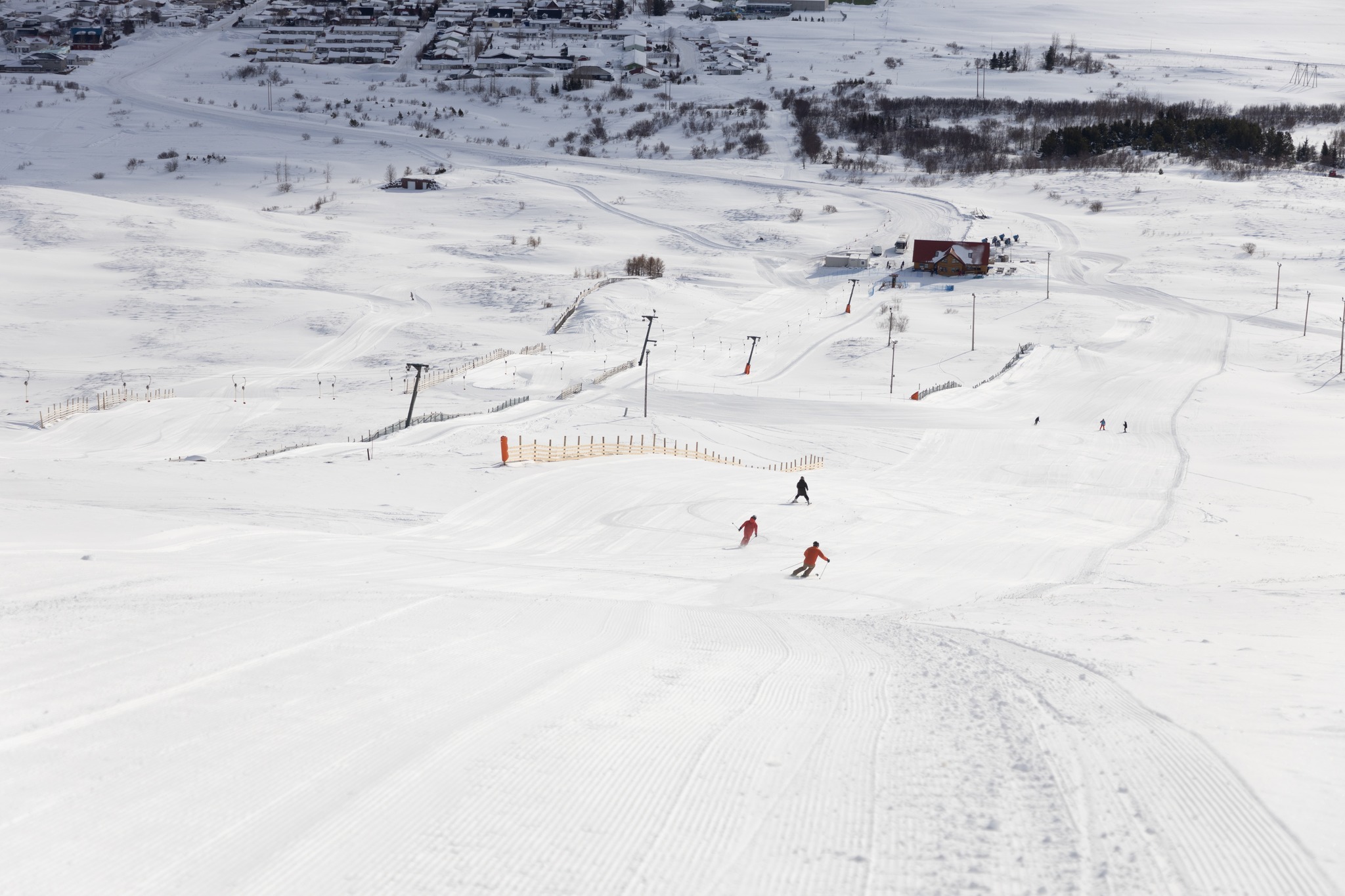 Skiers descending the compact Dalvík ski hill with the village behind