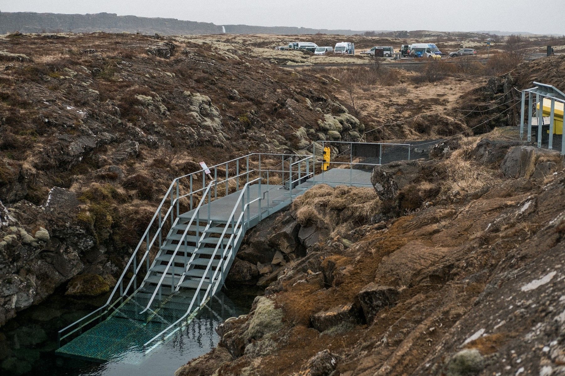 Metal entry platform at Silfra with guide vehicles and lava fields nearby.