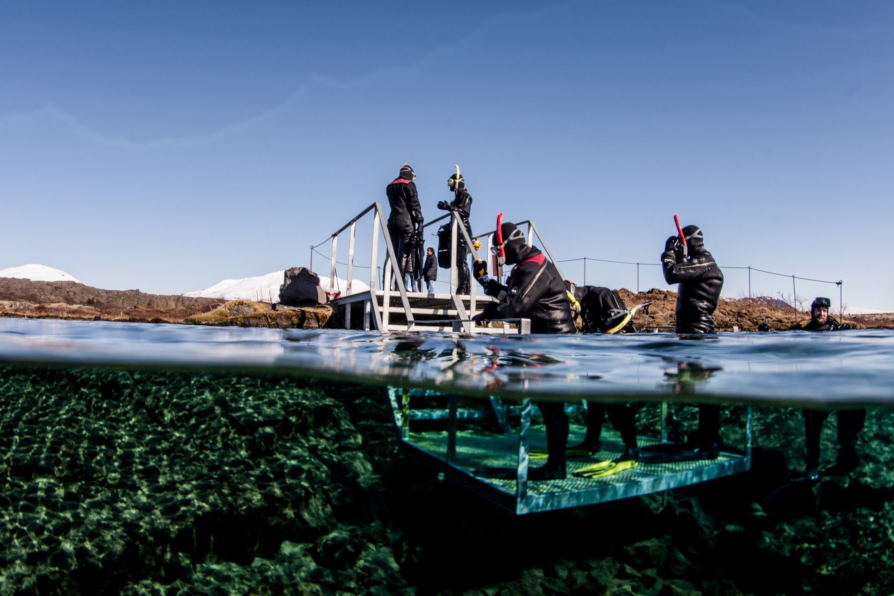 Snorkelers in cold-water gear at the Silfra exit platform.