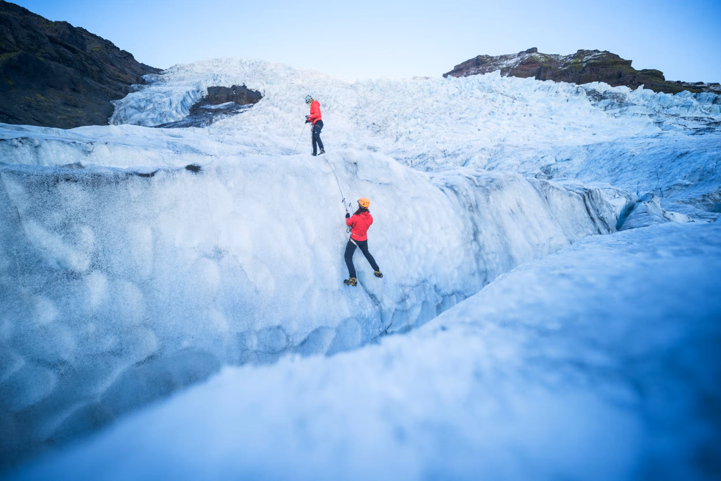 Guided glacier hikers crossing blue ice beside a crevasse in Skaftafell.