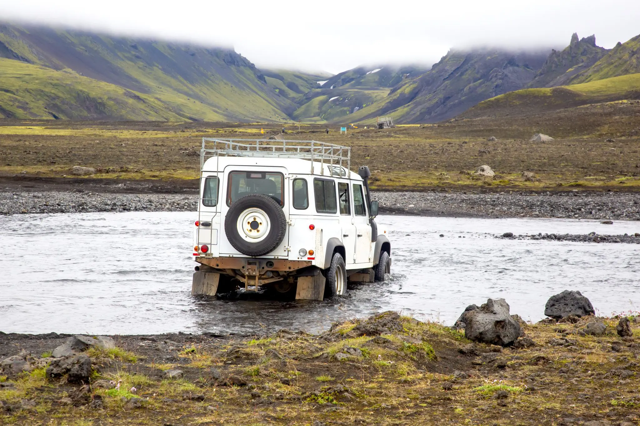 Four-wheel-drive vehicle crossing a shallow river on an established Icelandic highland route