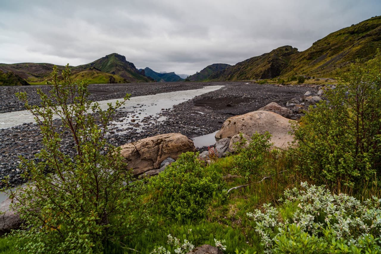 Braided Krossá riverbed below green Þórsmörk valley walls and low cloud