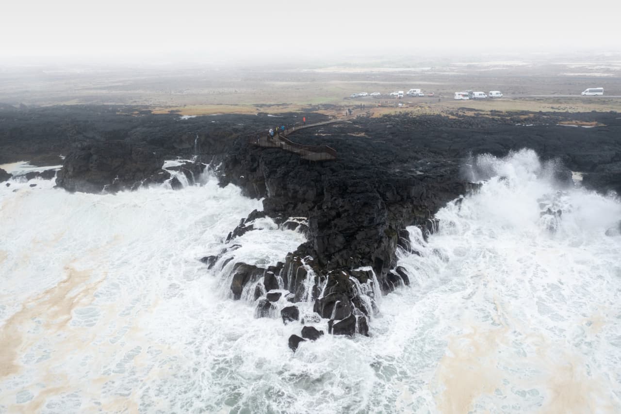 Heavy surf breaking around the Brimketill viewing platform on a dark lava coast