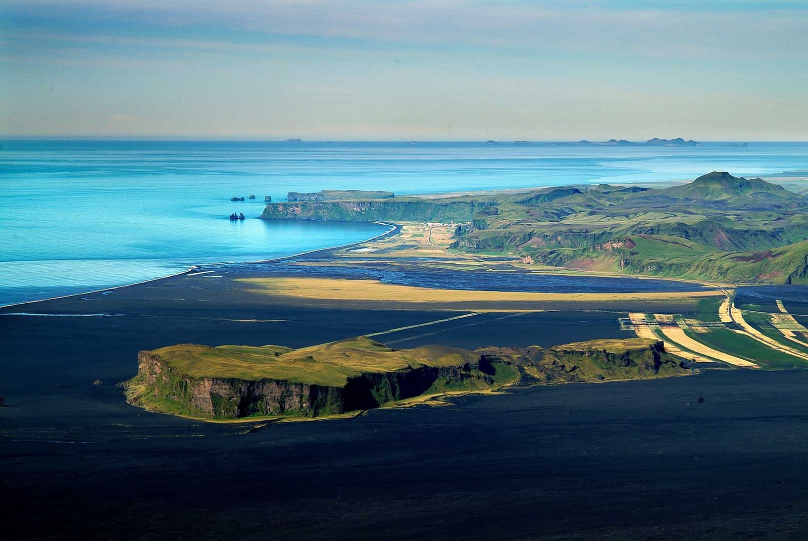 Aerial view of Hjörleifshöfði surrounded by black sand and the South Iceland coast