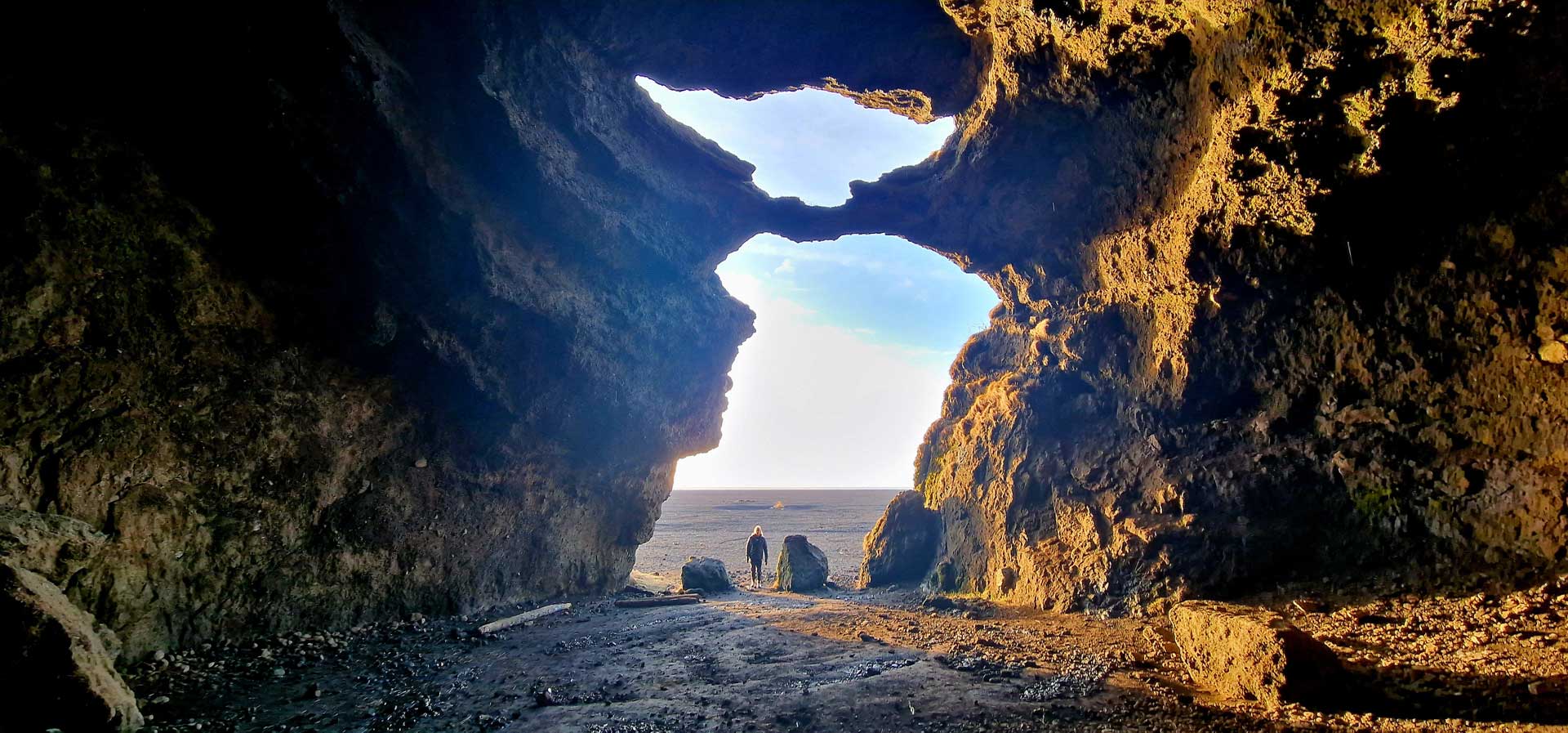 People standing inside Gígjagjá cave near its bright opening toward the South Iceland coast