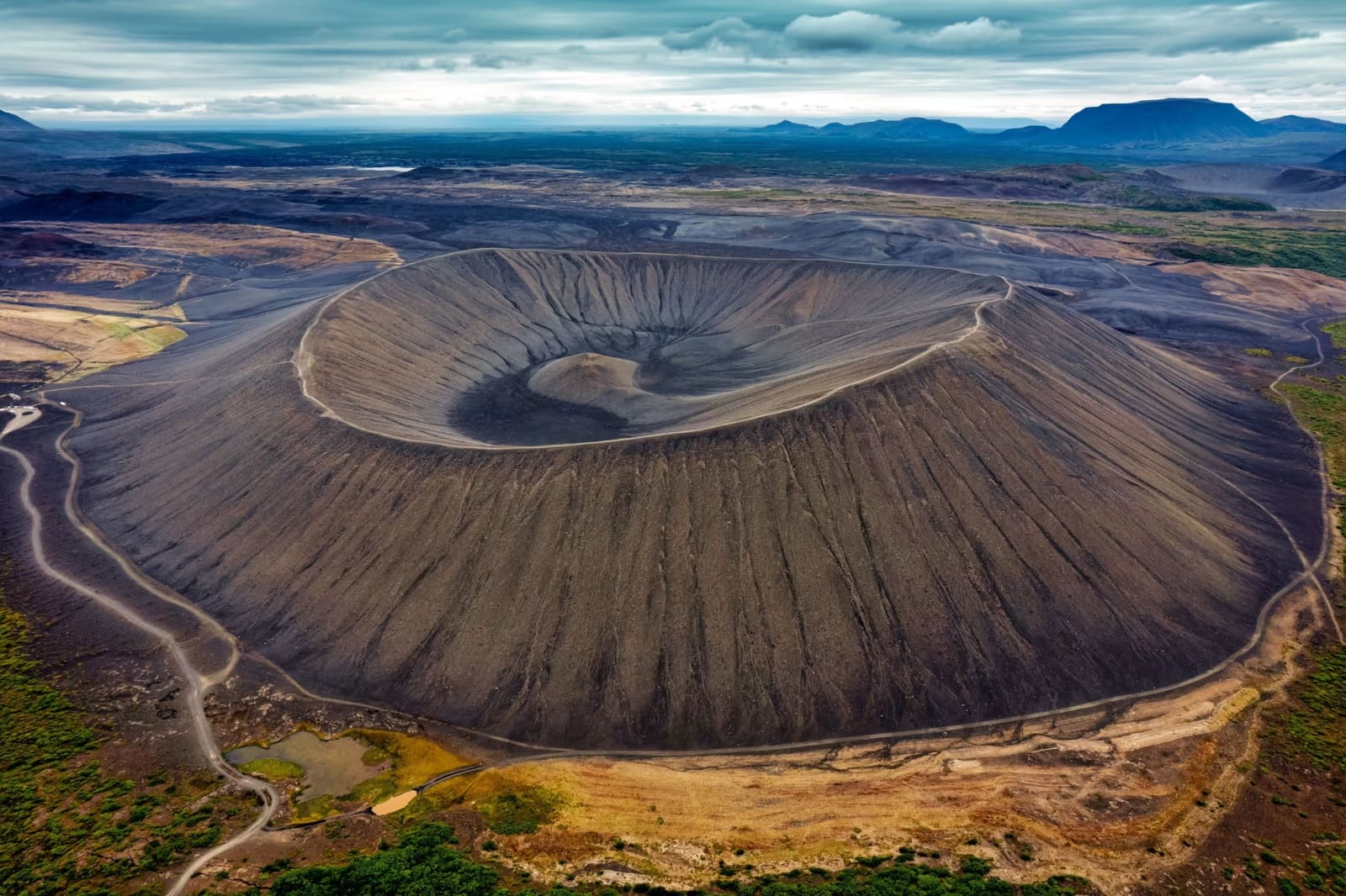 Aerial view across the broad dark ring of Hverfjall crater beside Lake Mývatn.