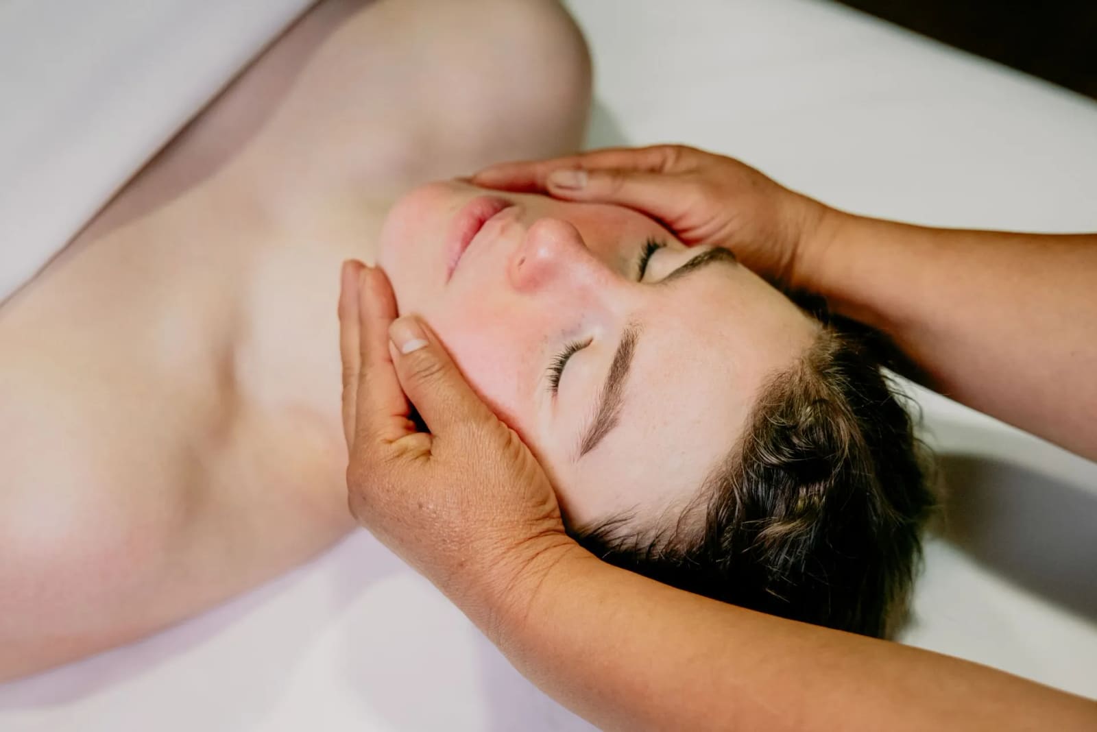 Practitioner supporting a guest's face and head during a spa treatment