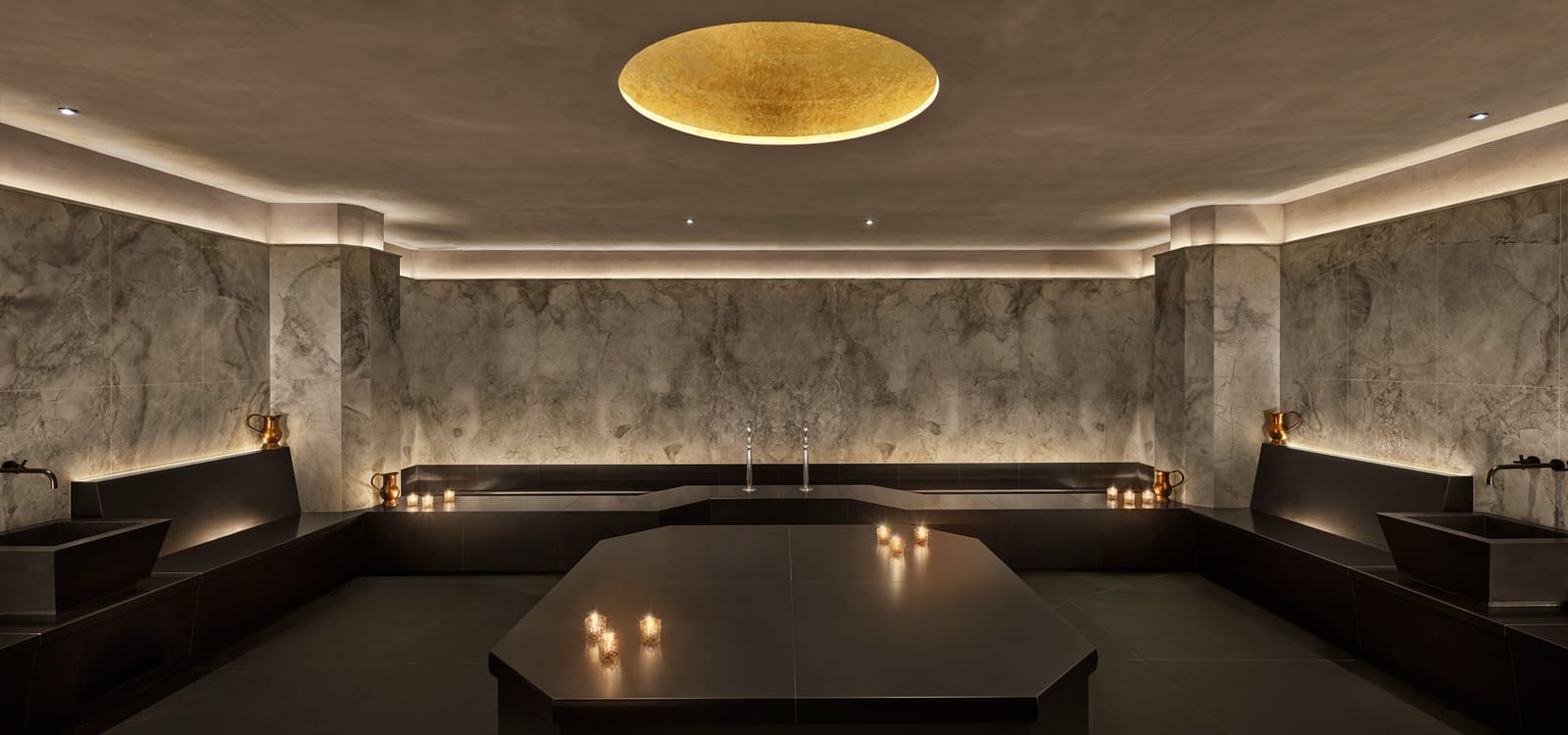 Dark stone hammam with a central heated table inside the Reykjavík EDITION Spa