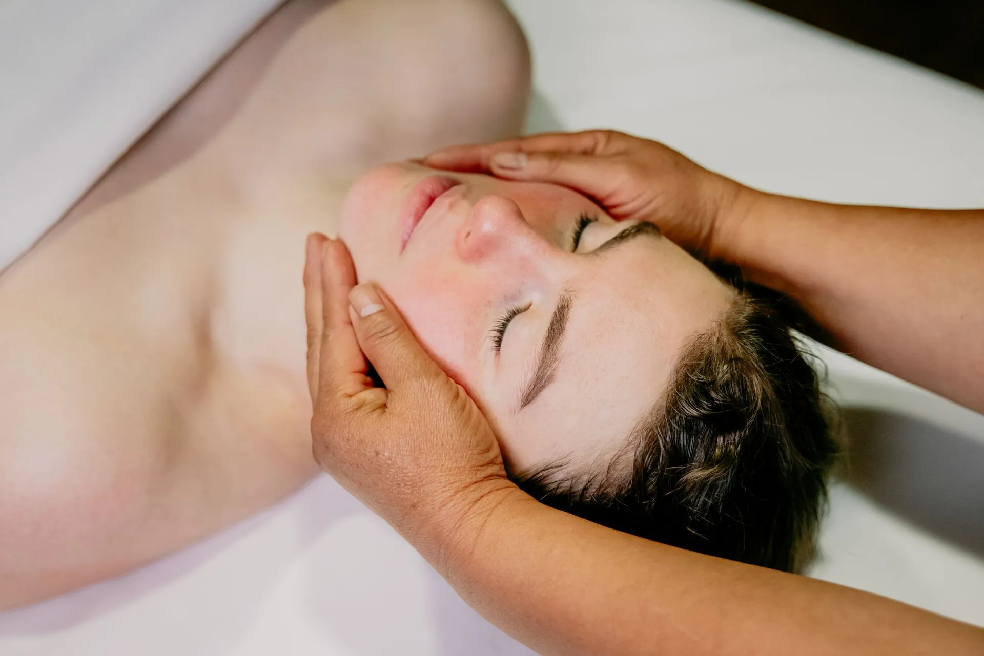 Practitioner supporting a guest's face and head during a spa treatment