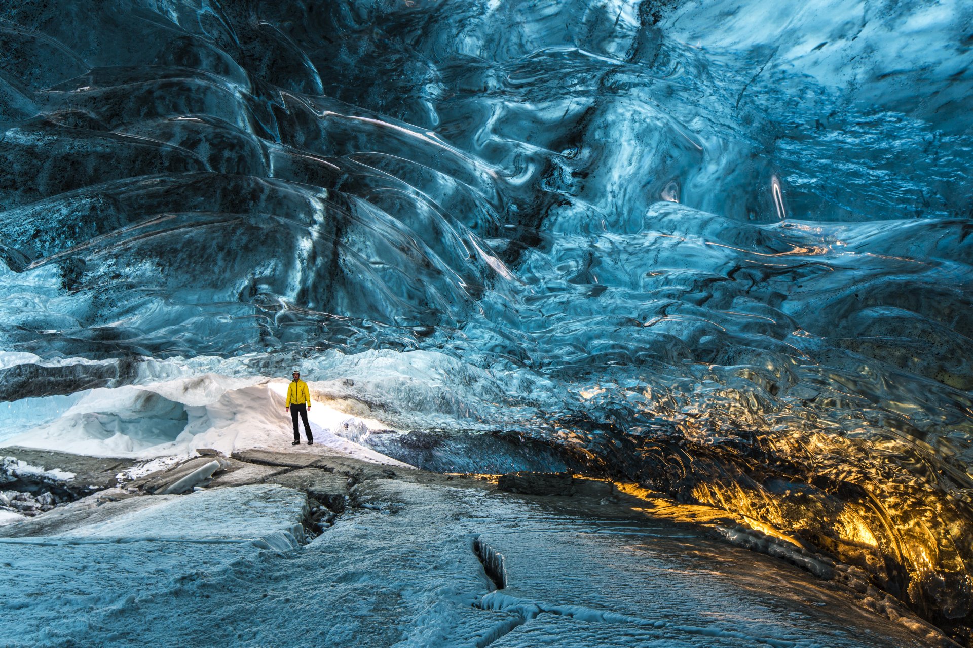Person standing beneath blue ice inside a South Iceland ice cave.