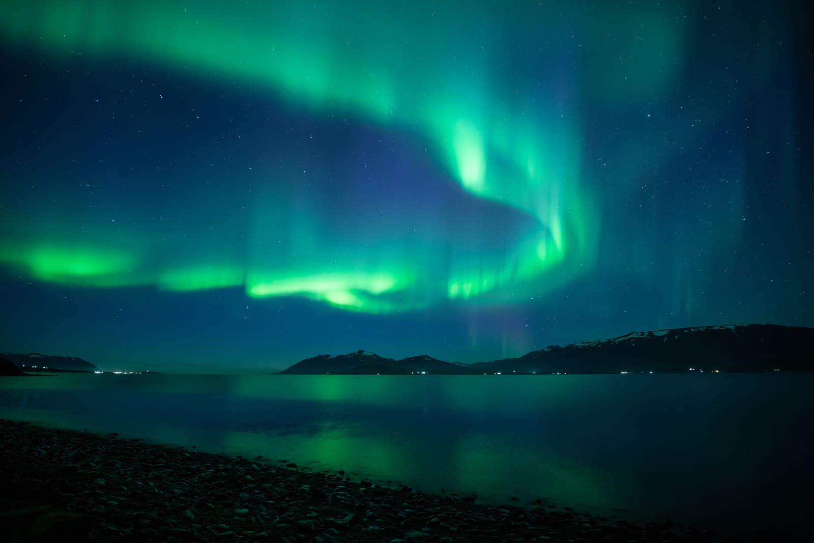 Northern lights over dark Icelandic mountains and water