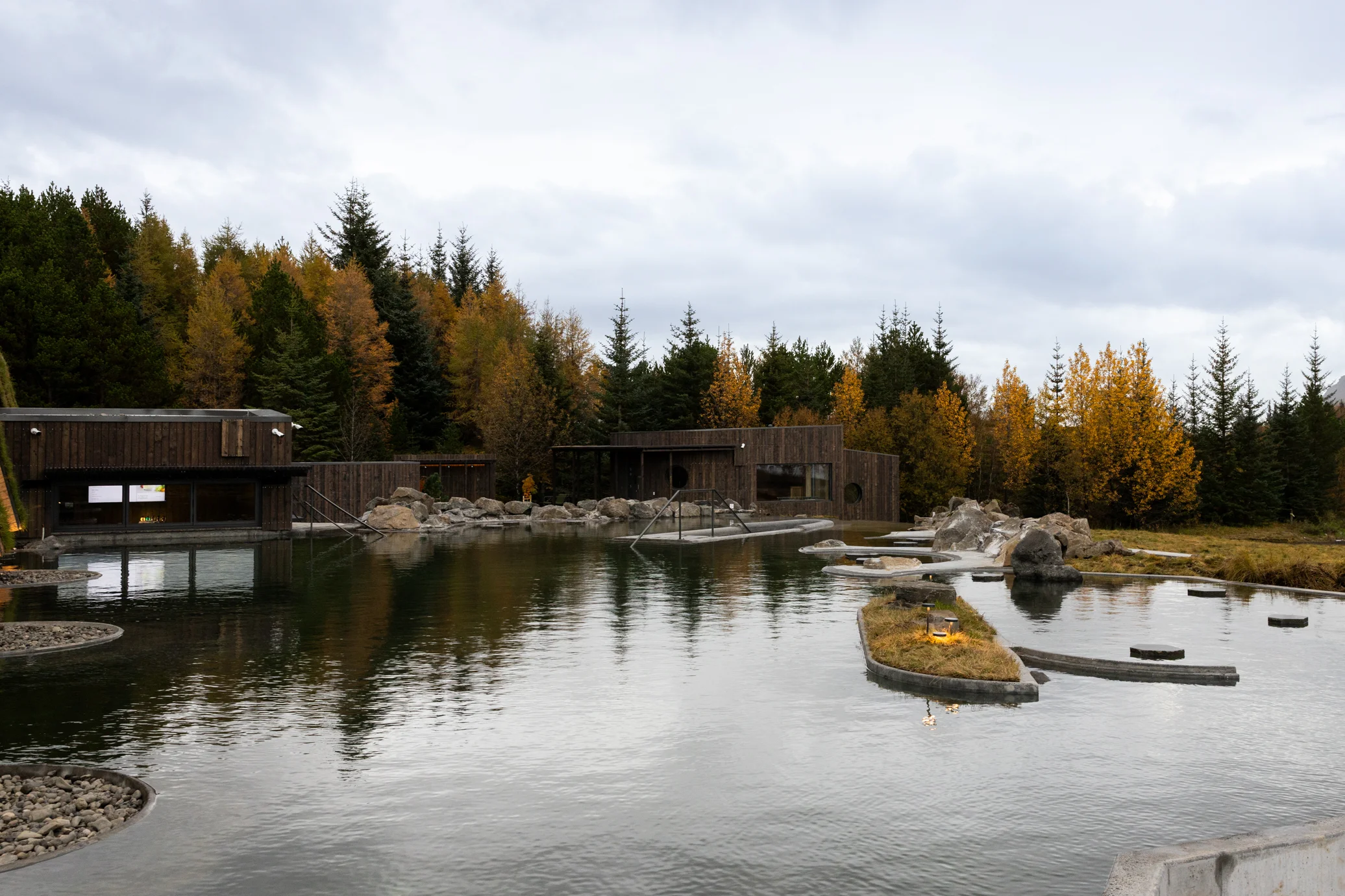 Laugarás Lagoon pools and timber buildings among autumn trees