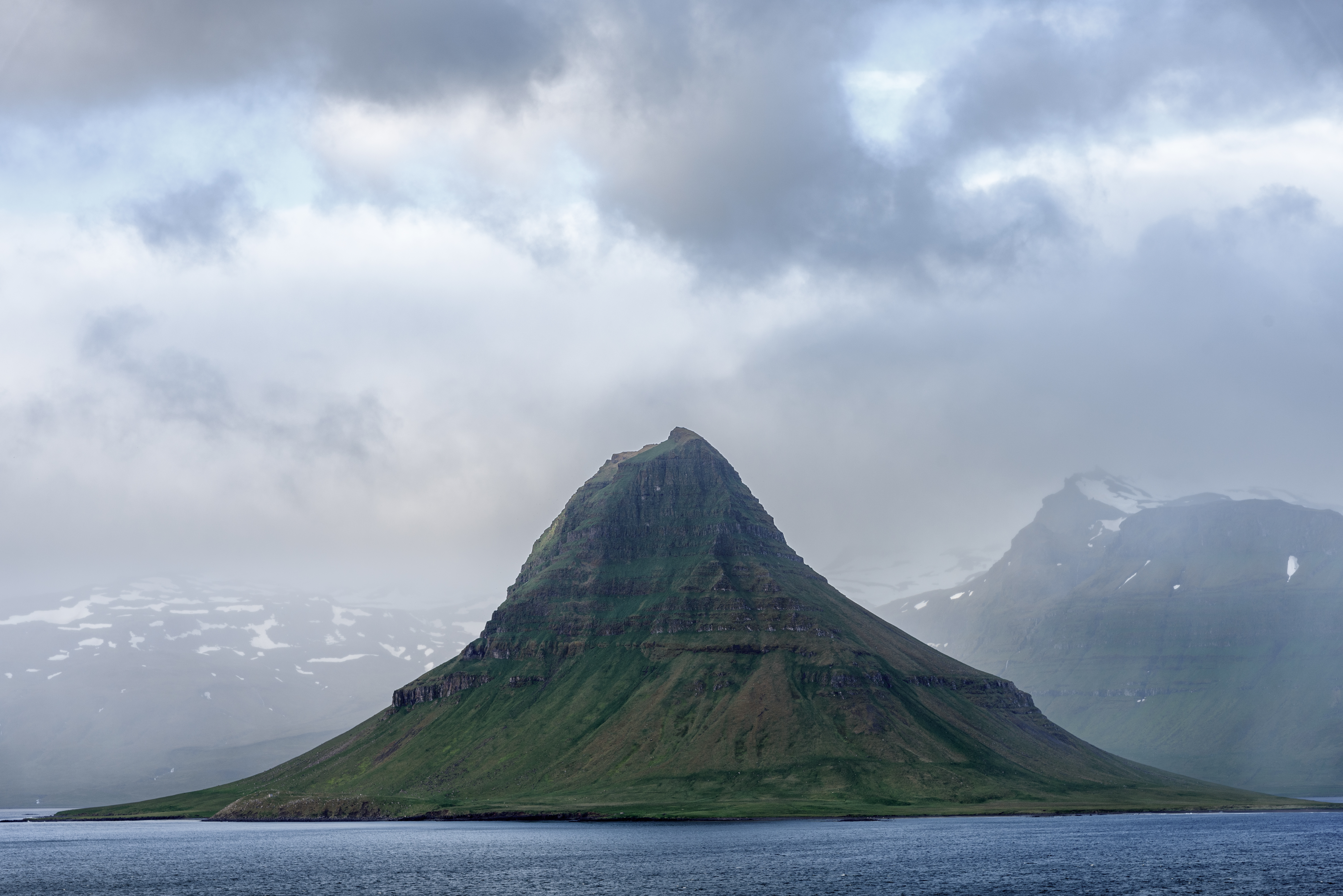 Kirkjufell mountain across the water near Grundarfjörður under low cloud