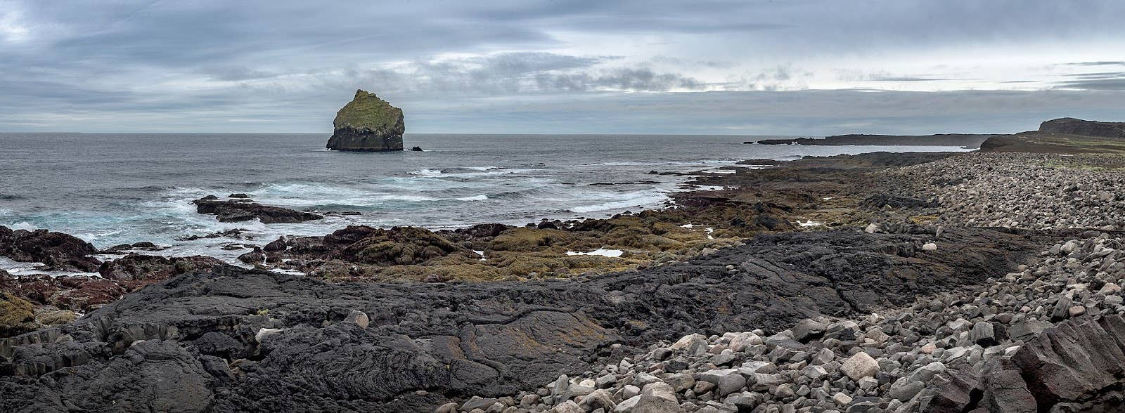 Wide coastal view of Valahnúkamöl with boulders, cliffs, and Atlantic water.