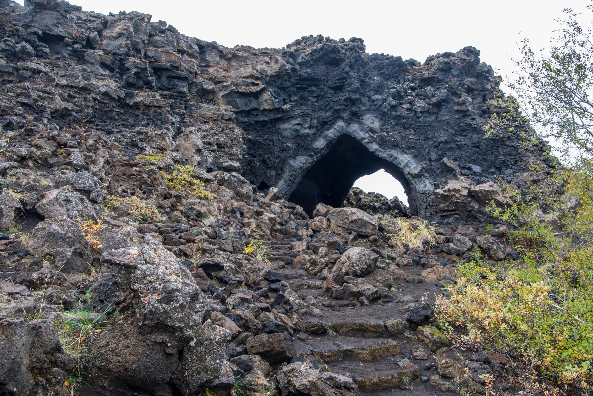 Kirkjan lava arch at Dimmuborgir with rough rock steps leading into the dark opening.