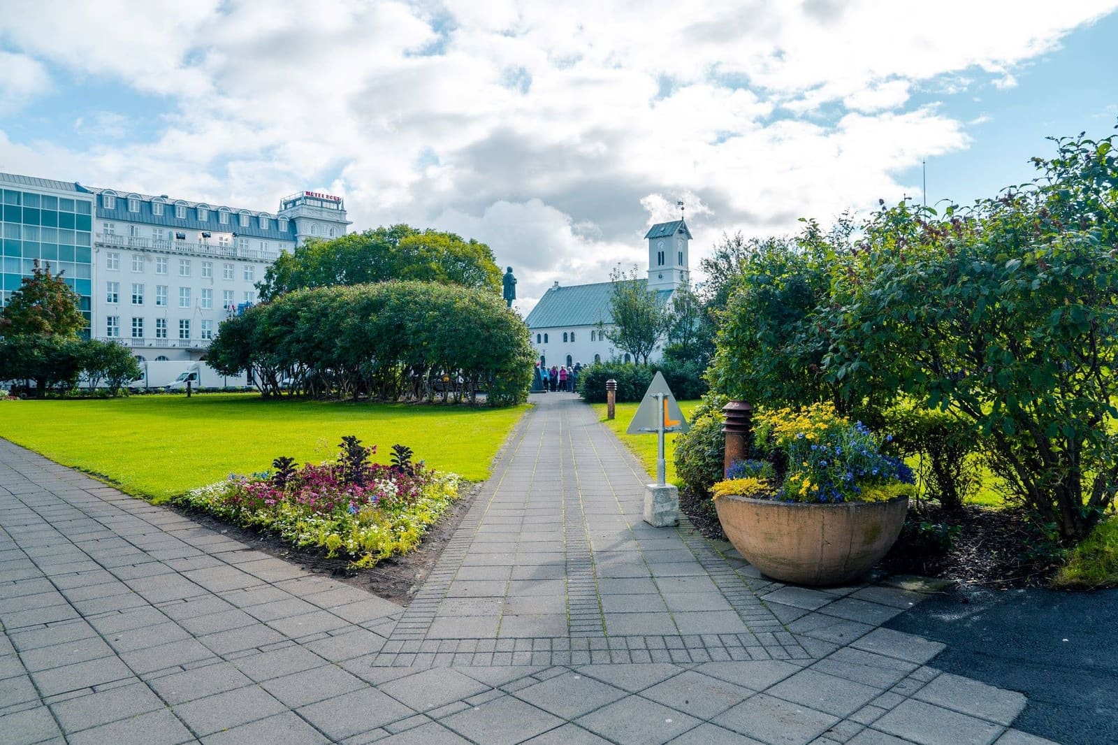Austurvöllur square in central Reykjavík with grass, people, and surrounding old-center buildings.