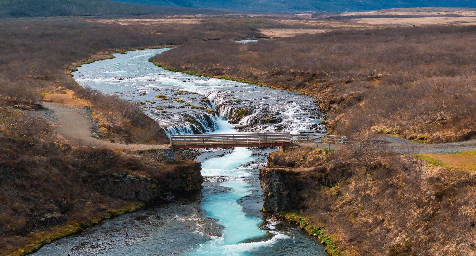 Aerial view of the bridge and blue Brúará channel at Brúarfoss Waterfall.