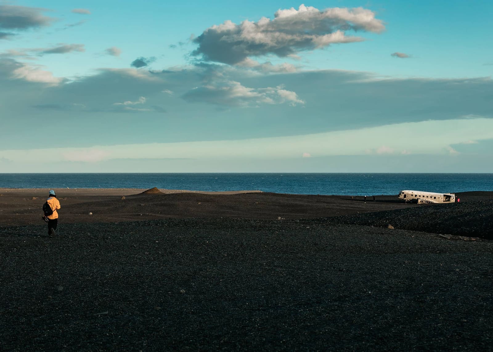 A person walking across Sólheimasandur toward the DC-3 Plane Wreck in South Iceland.
