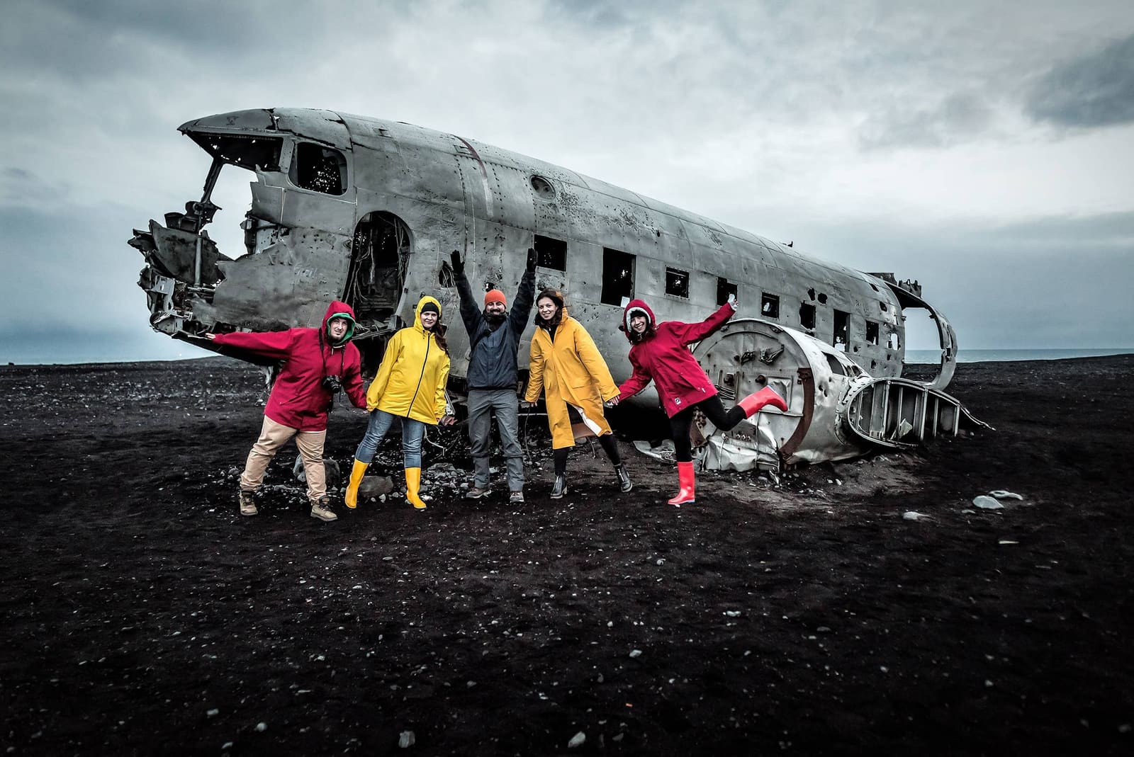 Travelers standing beside the DC-3 Plane Wreck on the black sand at Sólheimasandur.