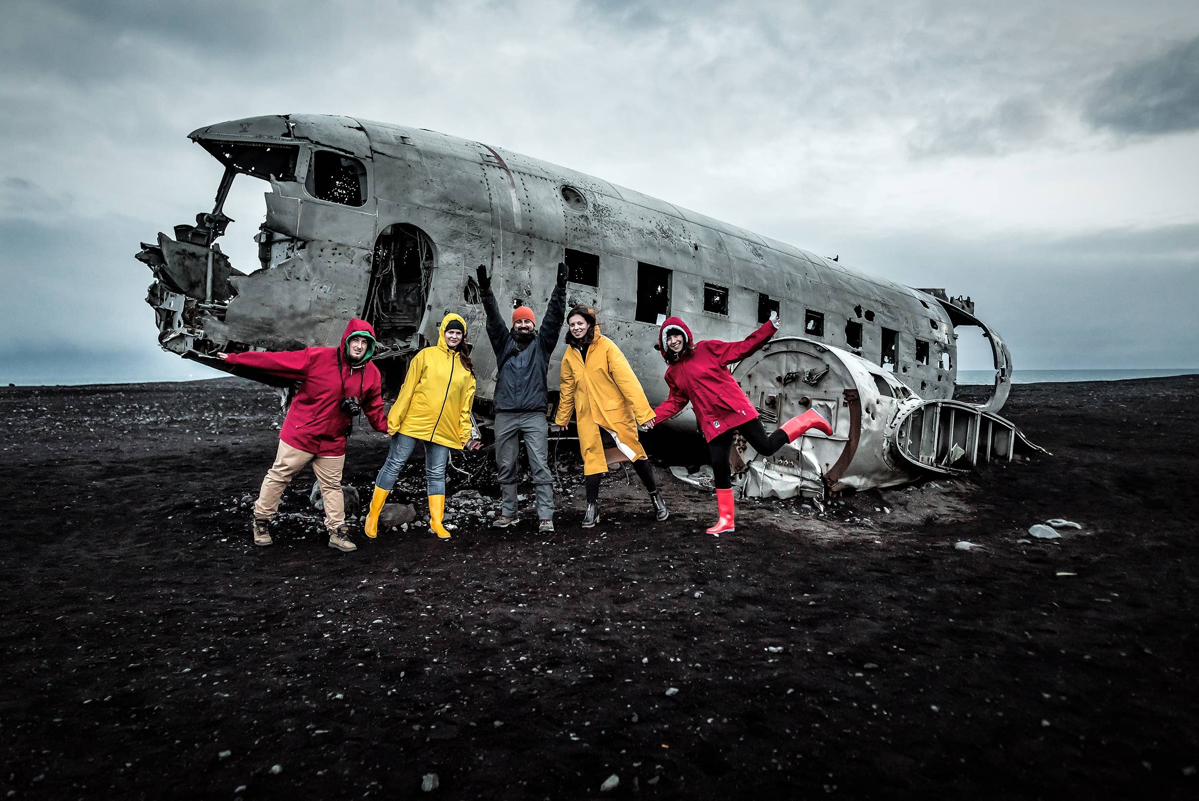 Travelers standing beside the DC-3 Plane Wreck on the black sand at Sólheimasandur.