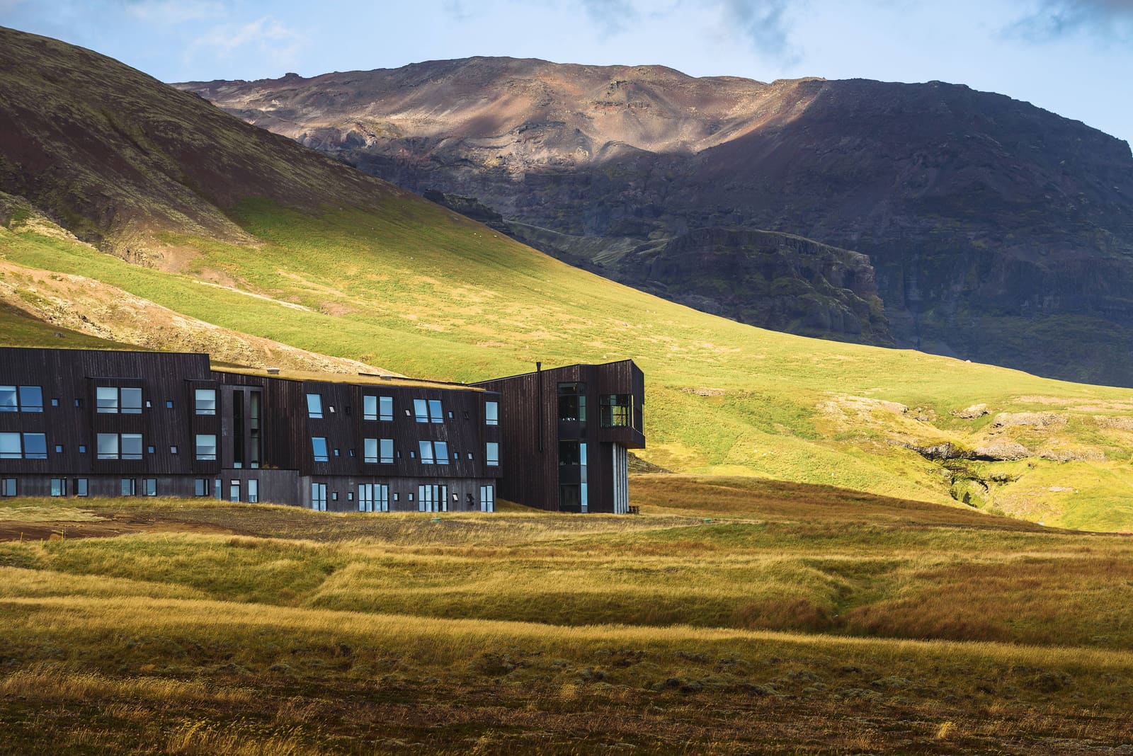 Hotel building and steep green cliffs in the Hnappavellir area of southeast Iceland.