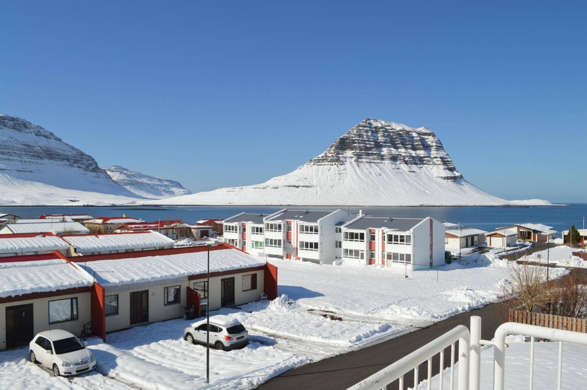 Snow-covered Kirkjufell seen across homes in Grundarfjörður on a clear winter day