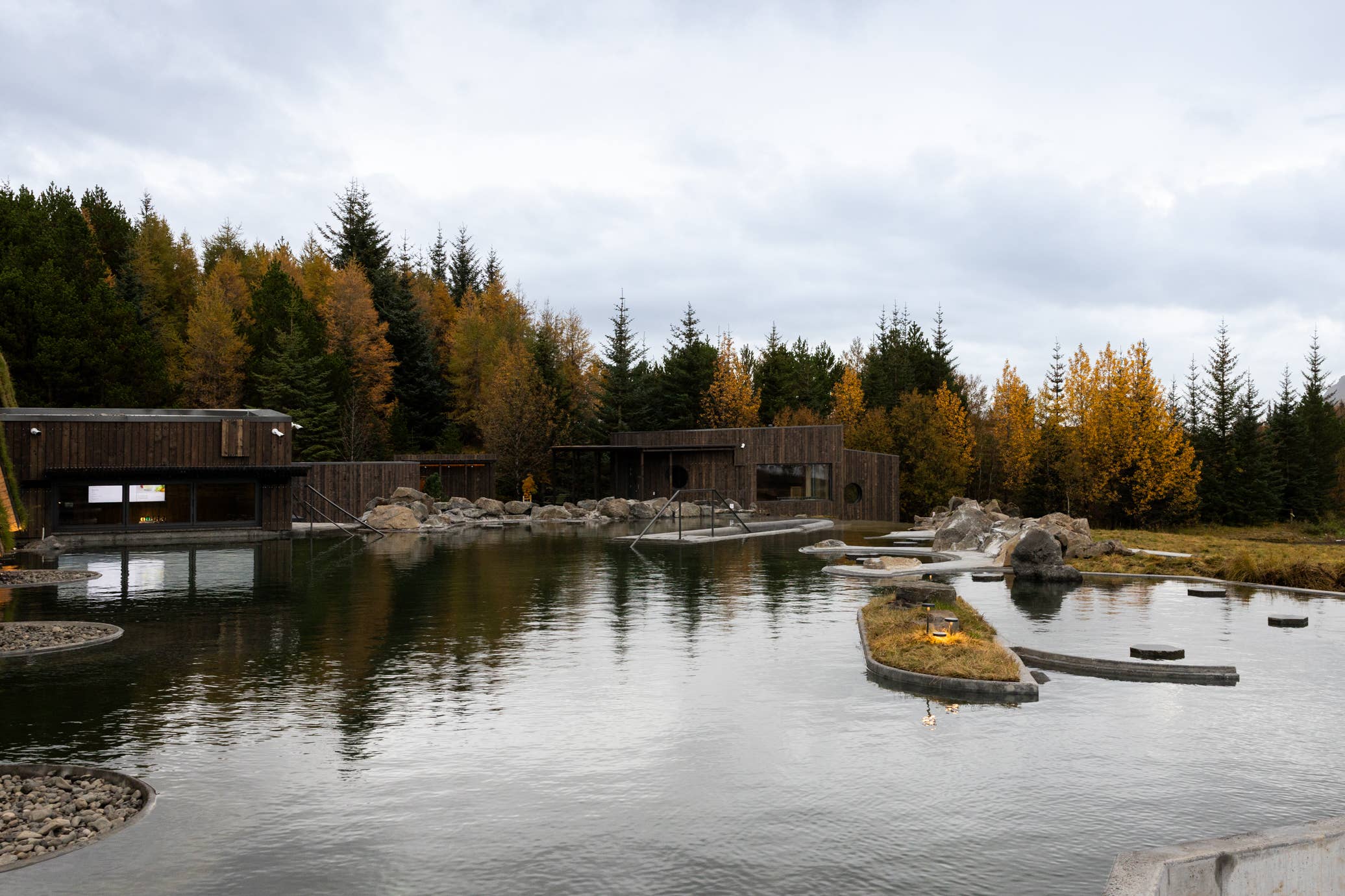 Geothermal water at Laugaras Lagoon surrounded by autumn trees in South Iceland.